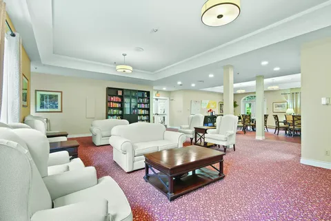 White sofas and armchairs on a red carpet beside dining tables