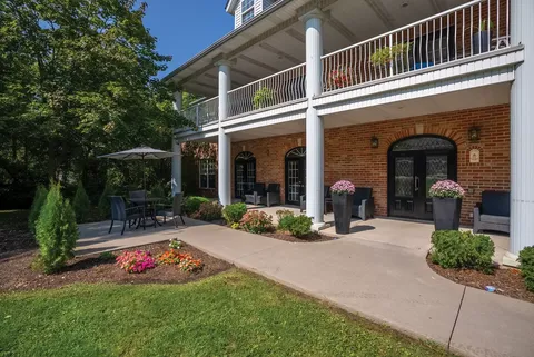 Brick residence building with a columned balcony and landscaped patio