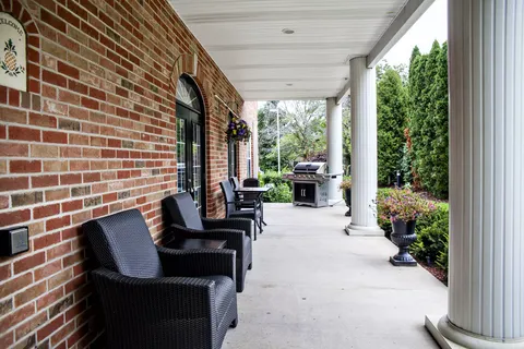 Covered brick porch with chairs, columns and exterior doors