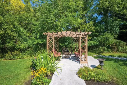 Garden path leading to a wooden pergola surrounded by flower beds