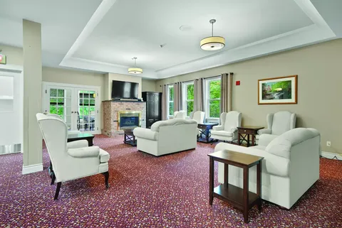 Lounge with white armchairs, a fireplace and a television
