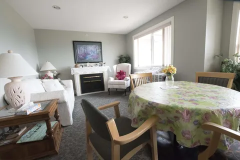 Room with armchairs, a fireplace and a round table with a floral cloth
