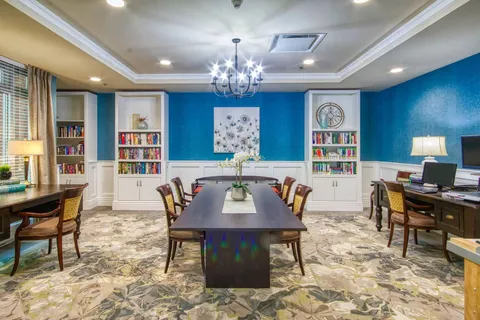 Library and meeting room with bookshelves, tables and chandelier.