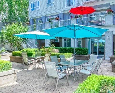 Patio tables beneath umbrellas beside the residence.