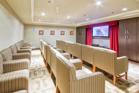 Screening room with rows of seats and red curtains.