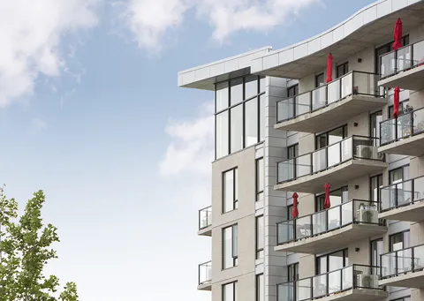 Modern grey residence with glass balcony railings and folded red umbrellas