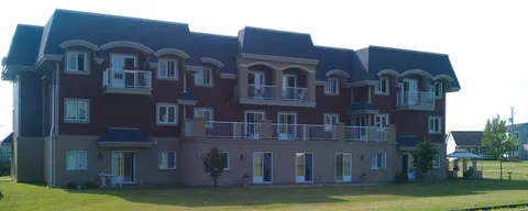 Rear of a three-storey residence with balconies, ground-floor doors and a lawn