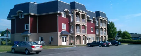 Three-storey residence with red cladding, arched balconies and cars in the parking area
