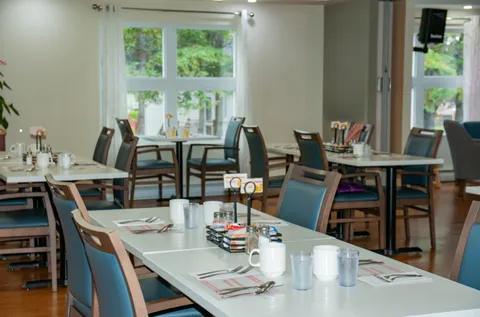 Dining room with tables, blue chairs and large windows
