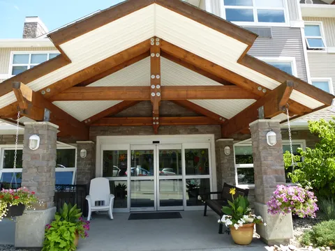 Covered entrance with timber beams, stone columns and planters.