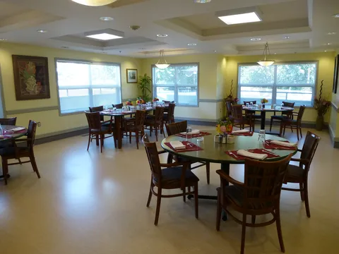 Dining room with set tables and chairs beside large windows.