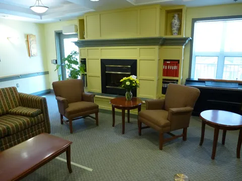 Sitting room with armchairs, a fireplace and windows.