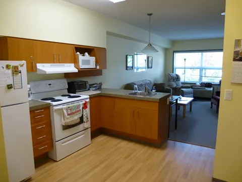 Suite kitchenette with cabinets, stove, sink and a breakfast counter.