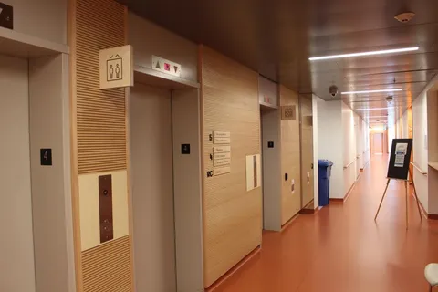 Corridor with elevators, wood wall panels and handrails