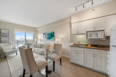 Kitchenette with white cabinets beside a round dining table and cream seating