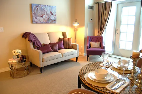 Sitting area with a cream sofa, purple chair and round dining table beside a glazed door