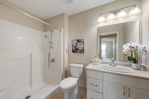 Bathroom with a shower, toilet, white vanity and floral wall picture