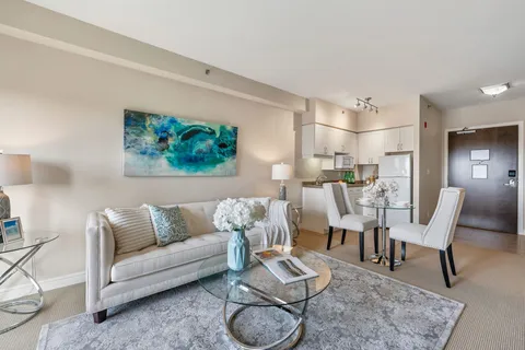 Sitting area with a cream sofa, glass coffee table and a kitchenette