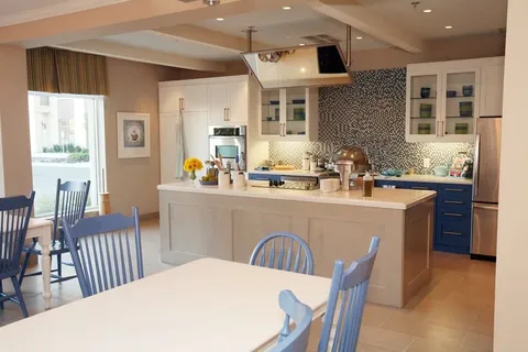 Kitchen with a large island, blue cabinets, tables and chairs