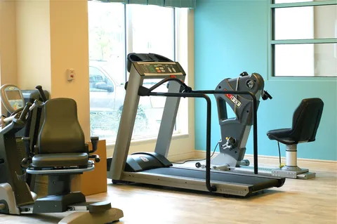 Fitness room with a treadmill and seated exercise machines beside large windows