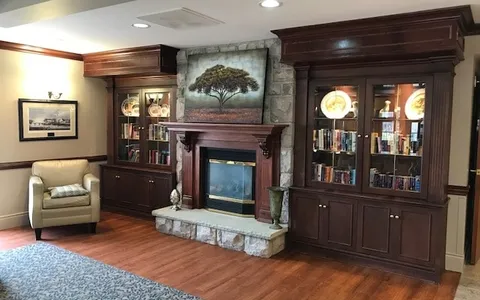 Armchair beside a stone fireplace and glass-fronted cabinets
