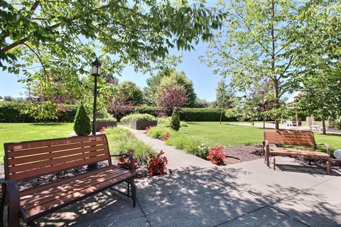 Garden path with benches, lawn, trees and flower beds.