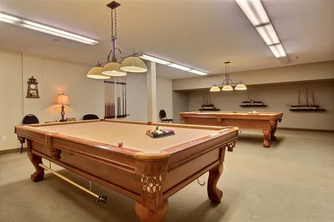 Billiards room with two pool tables and pendant lights.