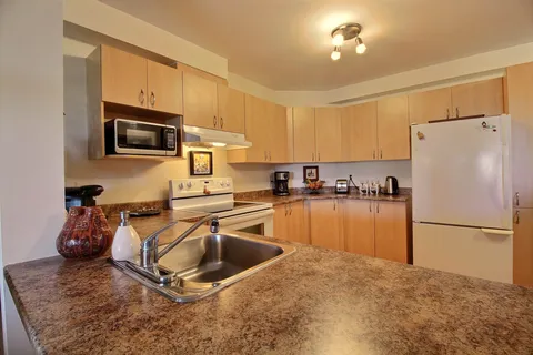Suite kitchen with wood cabinets, appliances and a countertop peninsula.