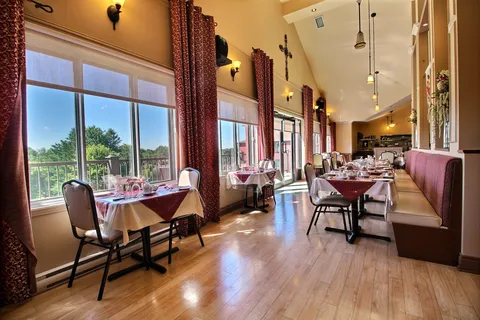 Dining room with tables along tall windows.