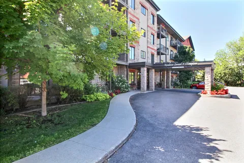 Residence facade and driveway with a covered entrance and trees.