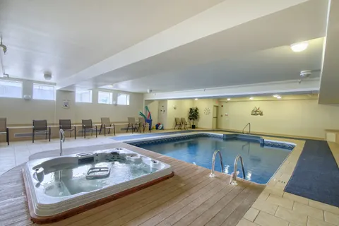 Indoor swimming pool and hot tub with surrounding tiled deck.