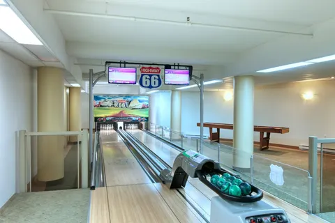 Indoor bowling lanes with scoring screens and a ball return.