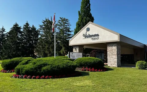 Residence entrance canopy beside flower beds, shrubs and lawn.