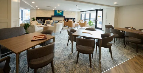 Lounge with upholstered seating, tables and a television.