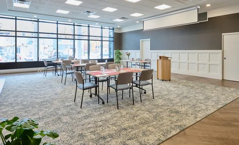 Activity room with tables, chairs and large windows.