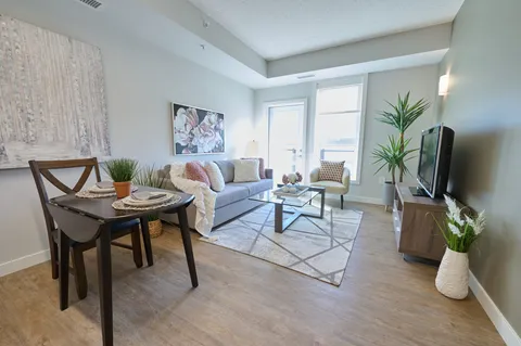 Suite living area with a sofa, dining table and balcony doors.