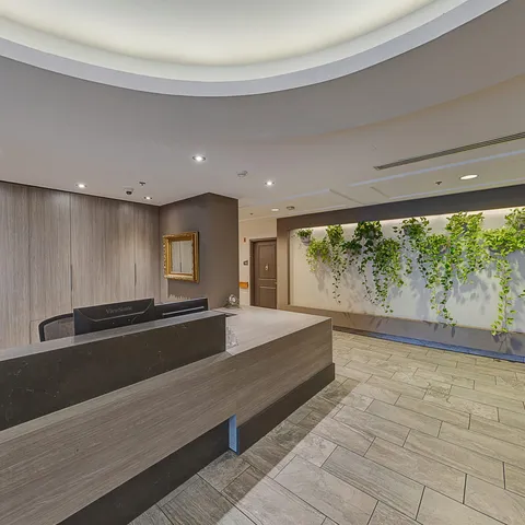 Reception desk with wood panels beside a green plant wall