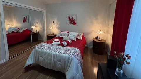 Bedroom with a double bed, patterned bedding, dresser and mirrored closet