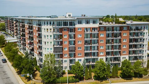 Aerial view of a brick residence with balconies, entrance canopy and parked cars