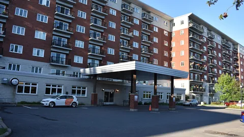 Residence entrance canopy beside brick walls, balconies and flower beds