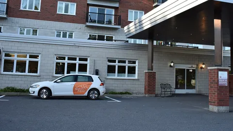 Covered entrance with glass doors, columns and a bench