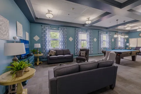 Blue-walled lounge with sofas, armchairs, a television and a pool table.