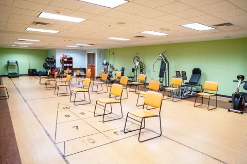 Exercise room with rows of chairs, fitness equipment and a floor shuffleboard court