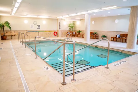 Indoor pool with a shallow stepped entrance, handrails and wooden benches