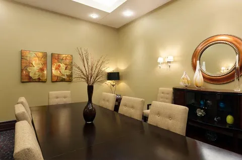 Long dining table with upholstered chairs and a large round mirror