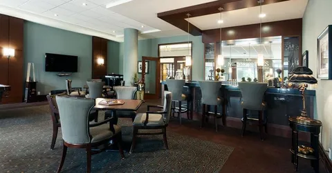 Tables and chairs beside a dark bar counter and large windows