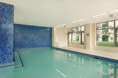 Indoor swimming pool with blue tiled walls and tall windows