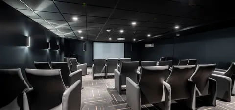 Cinema room with rows of padded chairs and a projection screen