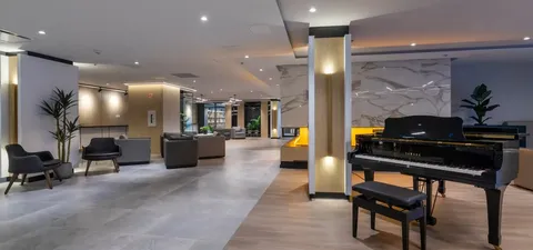 Grand piano and chairs beside a fireplace in an open sitting area