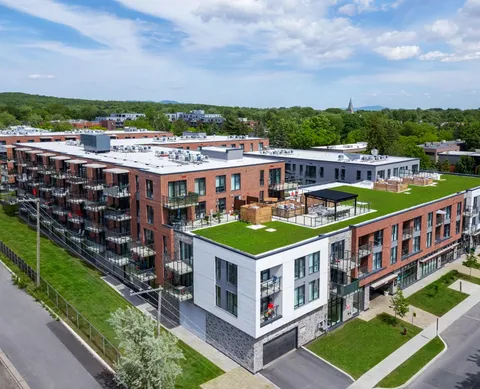 Aerial view of brick buildings with balconies and a rooftop lawn